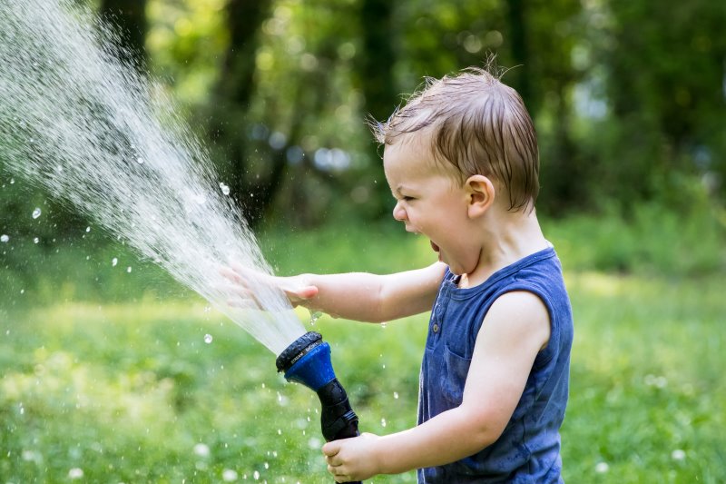Kind spielt mit einer Wasserbrause