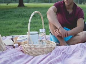 Mann sitzt auf Decke mit Picknickkorb