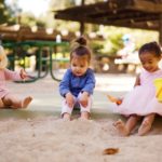 Drei Kinder, die im Sandkasten spielen